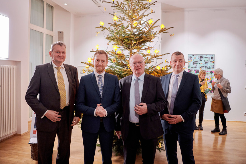 Männer stehen vor einem Weihnachtsbaum.