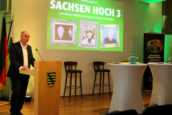 Redner steht am Pult vor einer Projektion