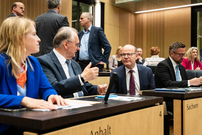 Personen sind in einem Plenarsaal im Gespräch.