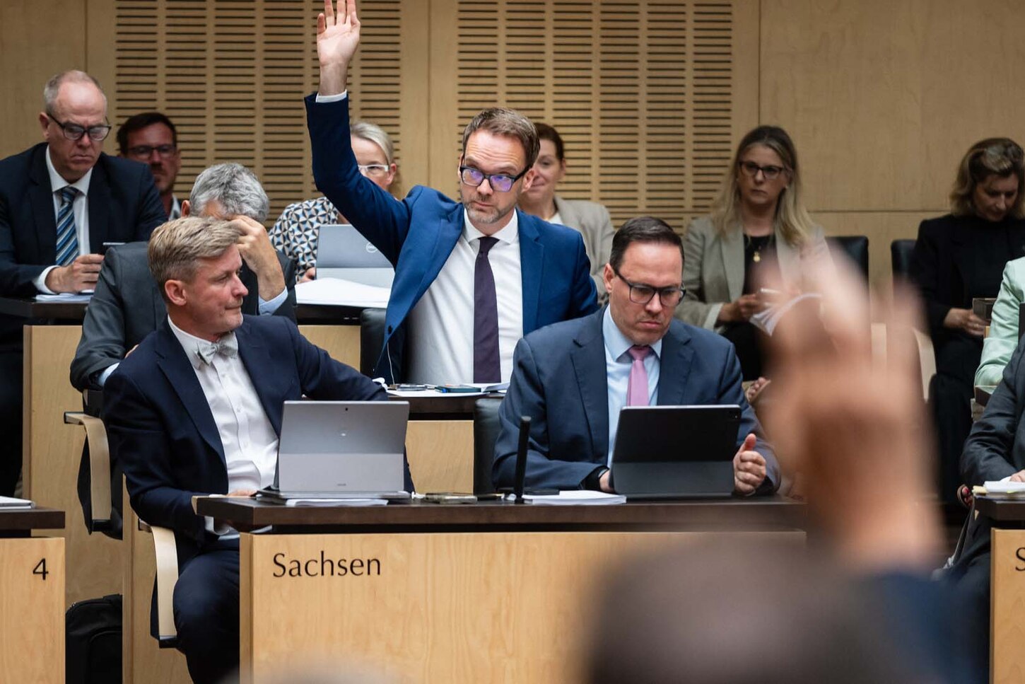 Mehrere Menschen sitzem in einem Sitzungssaal.