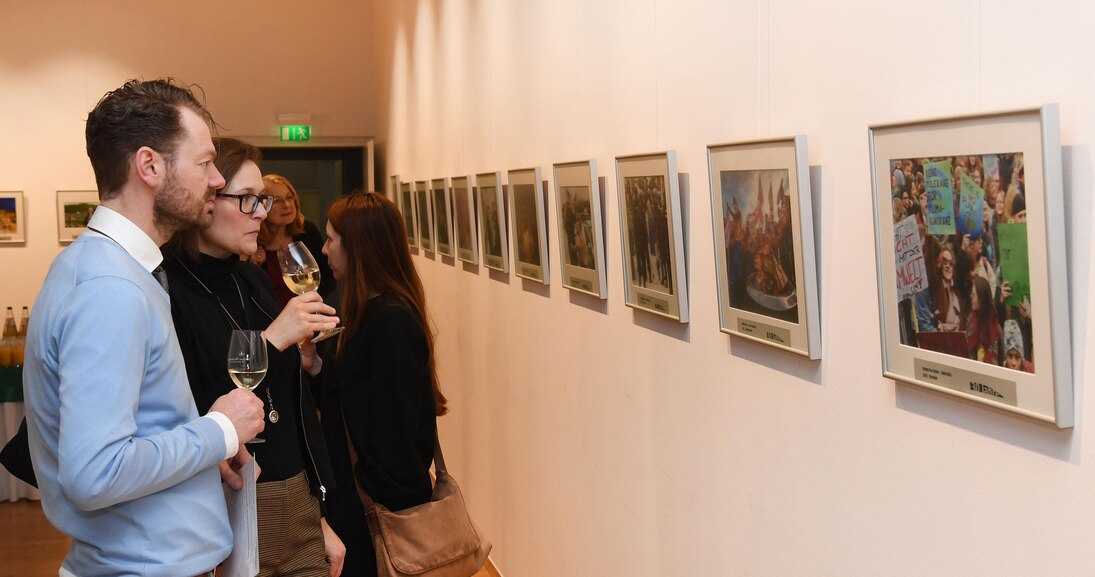 Ein Mann und eine Frau schauen sich Fotos an einer Wand an.