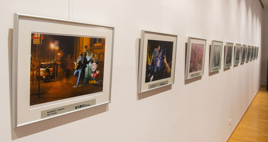 Eine Ausstellung zeigt Fotos an einer Wand.