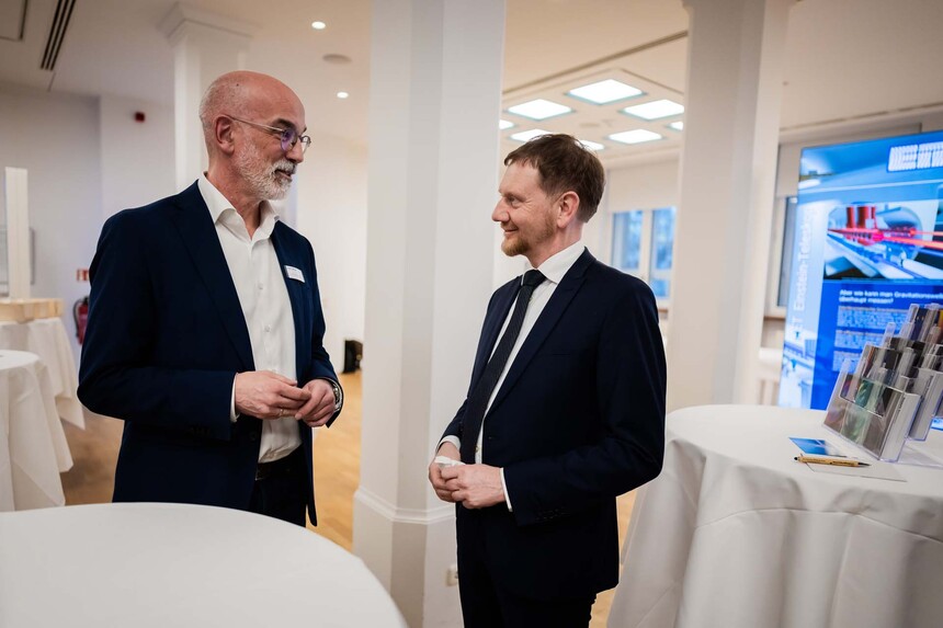 Zwei Männer sind an einem Stehtisch miteinander im Gespräch.