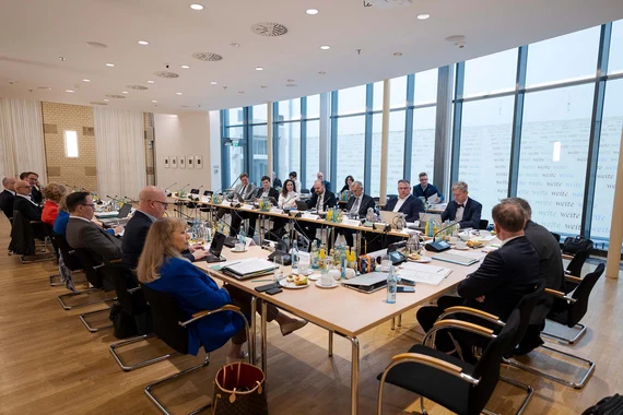 Mehrere Menschen sitzen in einem Konferenzssaal.