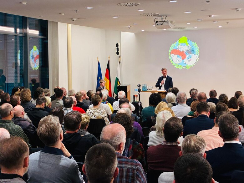 Ein Mann spricht auf einer Bühne vor Publikum.