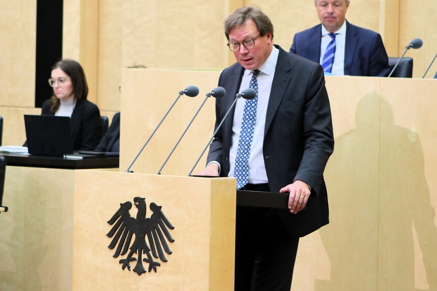 Ein Mann in Anzug und Krawatte spricht am Rednerpult