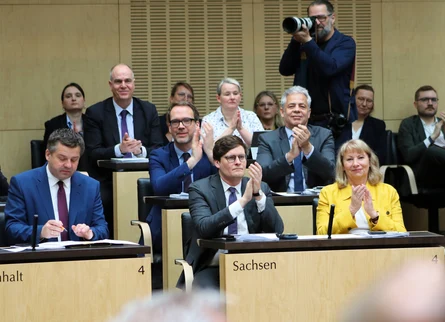 Personen sitzen im Plenarsaal und applaudieren