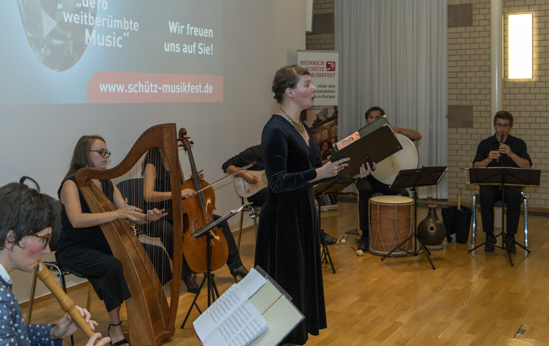 Künstler spielen Musik. Vor Ihnen steht eine Frau, die singt.